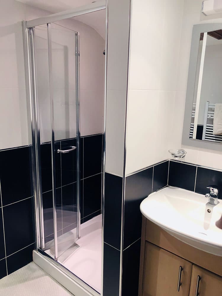 Shower room with a glass shower cubicle, black tiles and a vanity basin